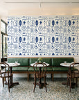 Desert Charms Indigo western icon wallpaper above a green leather banquette in a sunlit neighborhood cafe
