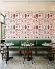 Desert Charms Oxblood western icon wallpaper above a green leather banquette in a sunlit neighborhood cafe