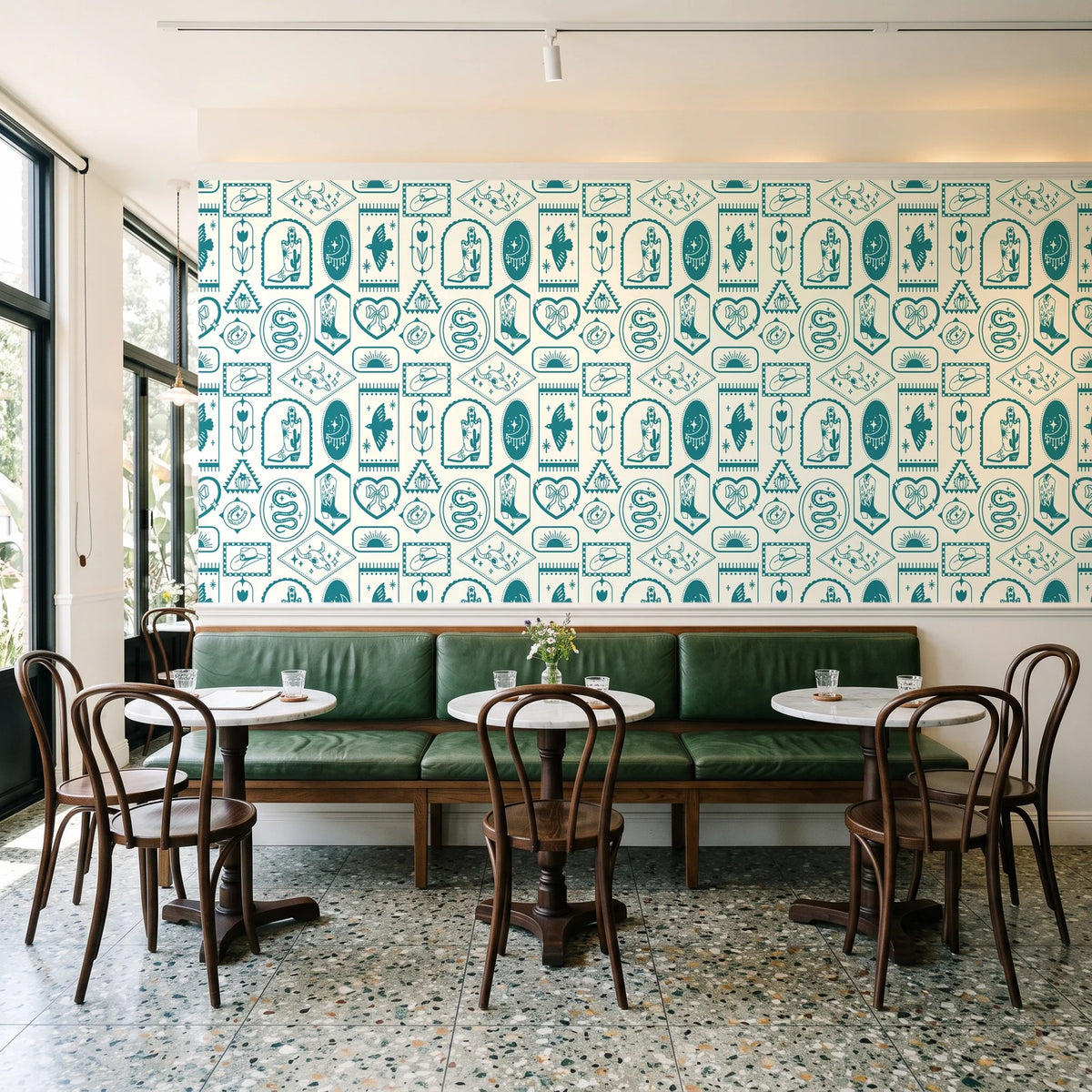 Desert Charms Turquoise western icon wallpaper above a green leather banquette in a sunlit neighborhood cafe