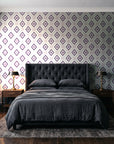 Desert Compass Aubergine geometric diamond wallpaper behind a tufted headboard in a dark, moody bedroom