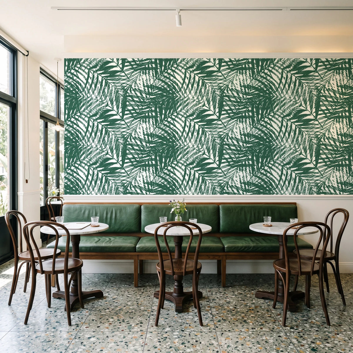 Desert Frond Emerald palm frond wallpaper above a green leather banquette in a sunlit neighborhood cafe