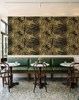 Desert Frond Gilt palm frond wallpaper above a green leather banquette in a sunlit neighborhood cafe
