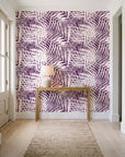 Desert Frond Plum palm frond wallpaper behind a console table in a light entry hallway