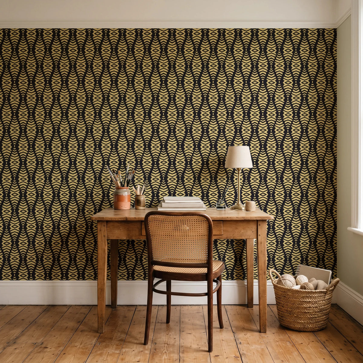 Desert Ritual Noir tribal geometric wallpaper behind a vintage writing desk in a cozy craft-room home office