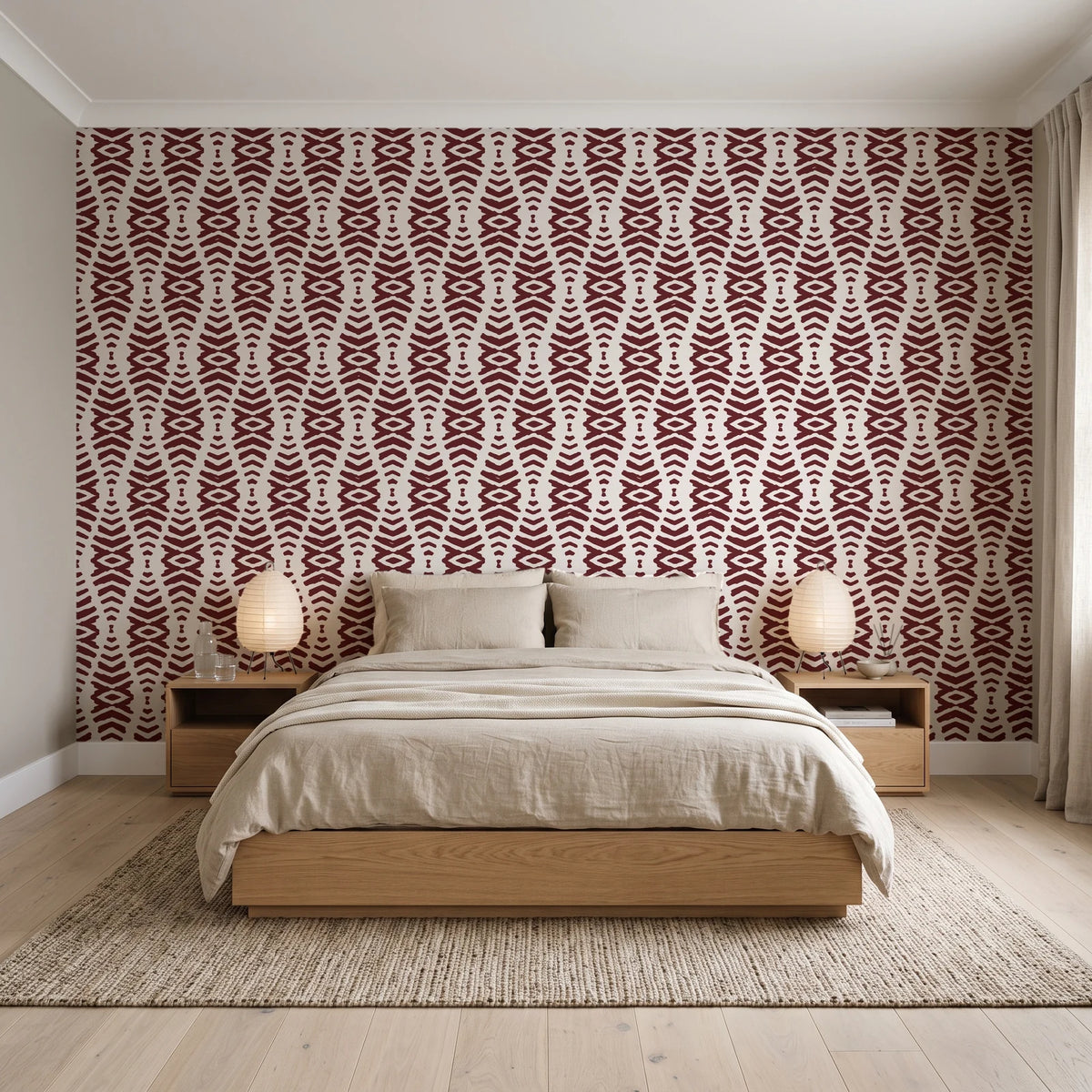 Desert Ritual Oxblood tribal geometric wallpaper behind a low platform bed in a serene Japandi bedroom