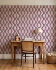 Desert Ritual Oxblood tribal geometric wallpaper behind a vintage writing desk in a cozy craft-room home office