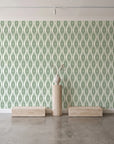 Desert Ritual Sage tribal geometric wallpaper behind a travertine pedestal and vase in a minimal boutique