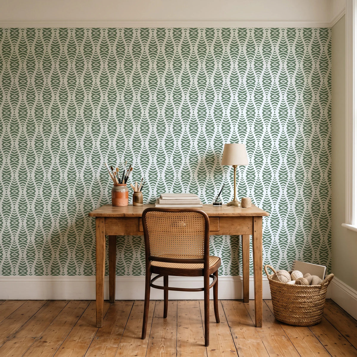 Desert Ritual Sage tribal geometric wallpaper behind a vintage writing desk in a cozy craft-room home office