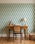 Desert Ritual Sage tribal geometric wallpaper behind a vintage writing desk in a cozy craft-room home office