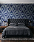 Diamond Echo Midnight tribal diamond wallpaper behind a tufted headboard in a dark, moody bedroom