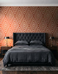 Diamond Echo Terracotta tribal diamond wallpaper behind a tufted headboard in a dark, moody bedroom