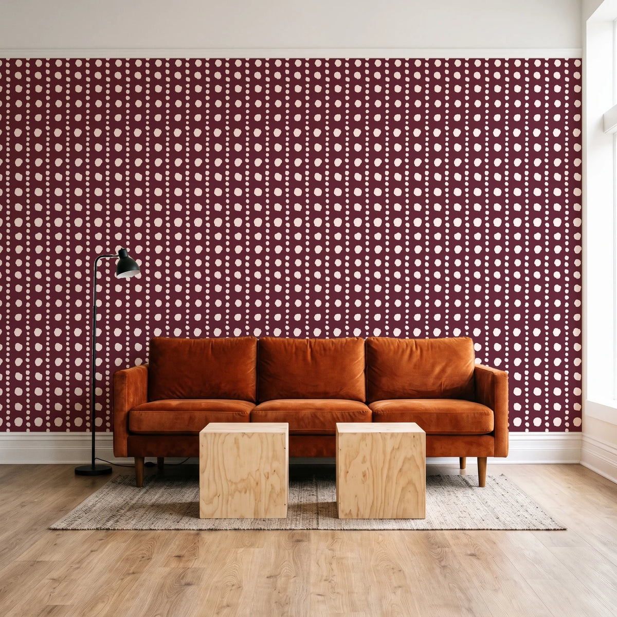 Dot Column Oxblood dotted wallpaper behind a rust velvet sofa in a bright coworking lounge