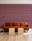 Dot Column Oxblood dotted wallpaper behind a rust velvet sofa in a bright coworking lounge
