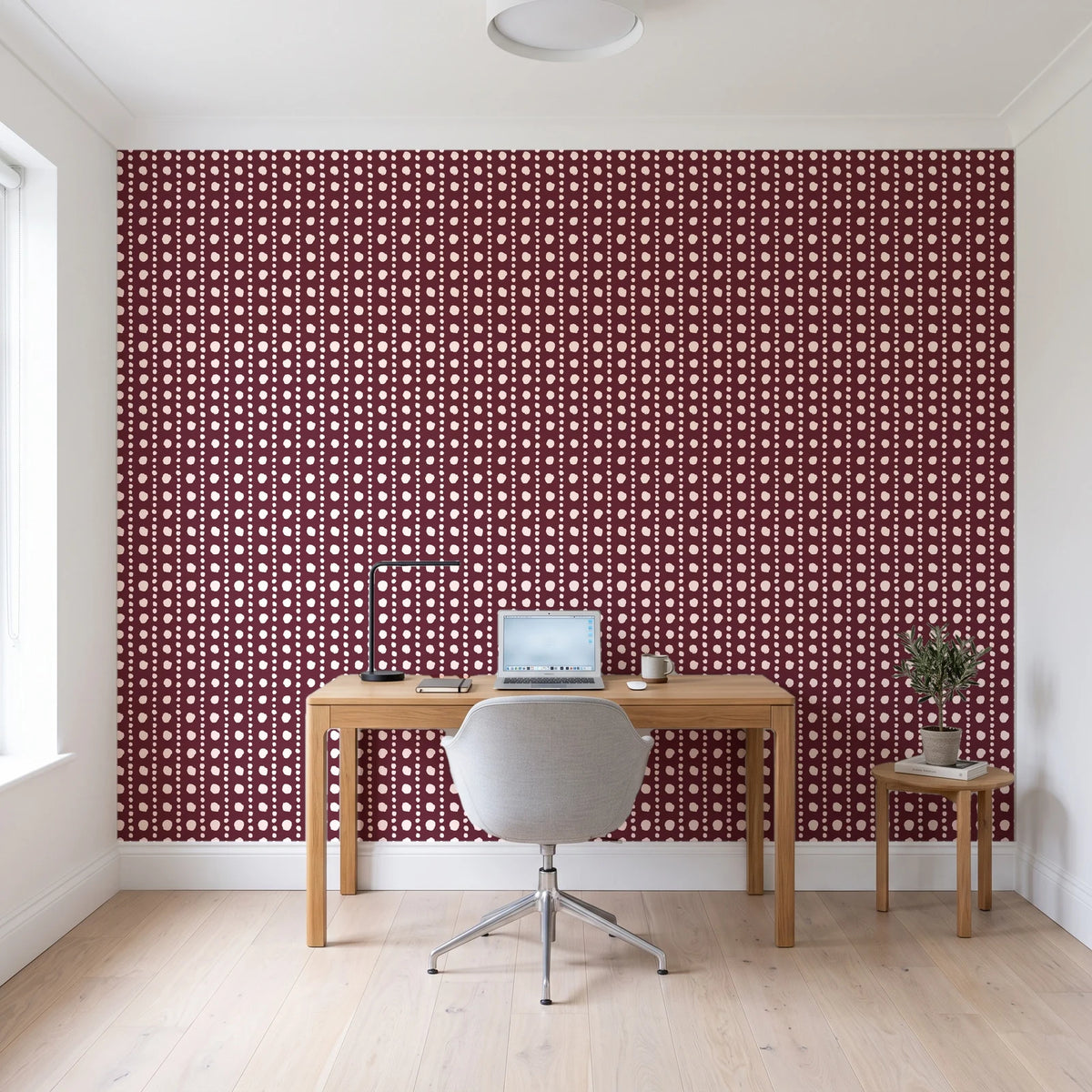 Dot Column Oxblood dotted wallpaper behind a modern oak desk in a bright home office
