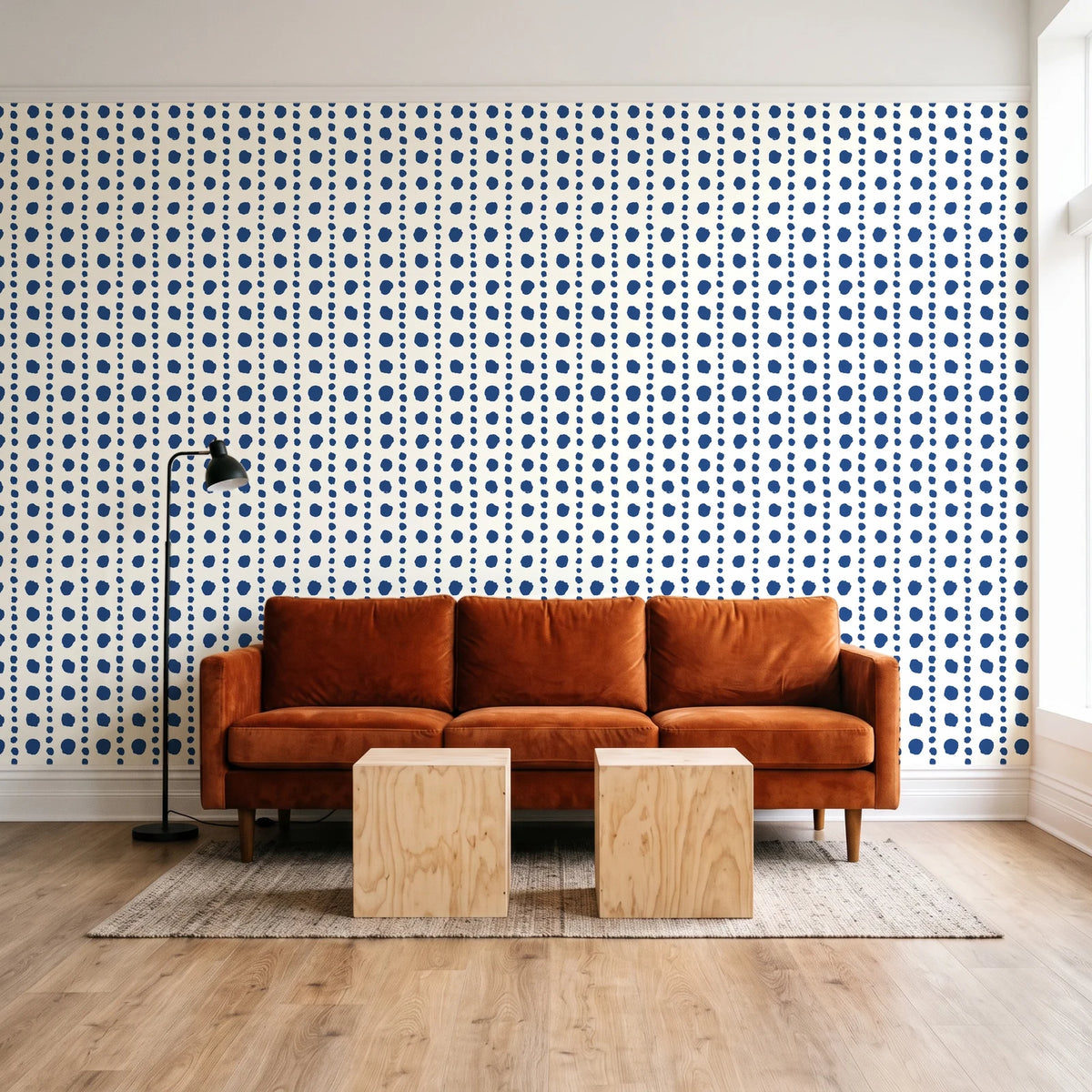 Dot Column Porcelain dotted wallpaper behind a rust velvet sofa in a bright coworking lounge