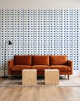 Dot Column Porcelain dotted wallpaper behind a rust velvet sofa in a bright coworking lounge