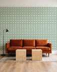 Dot Column Sage dotted wallpaper behind a rust velvet sofa in a bright coworking lounge