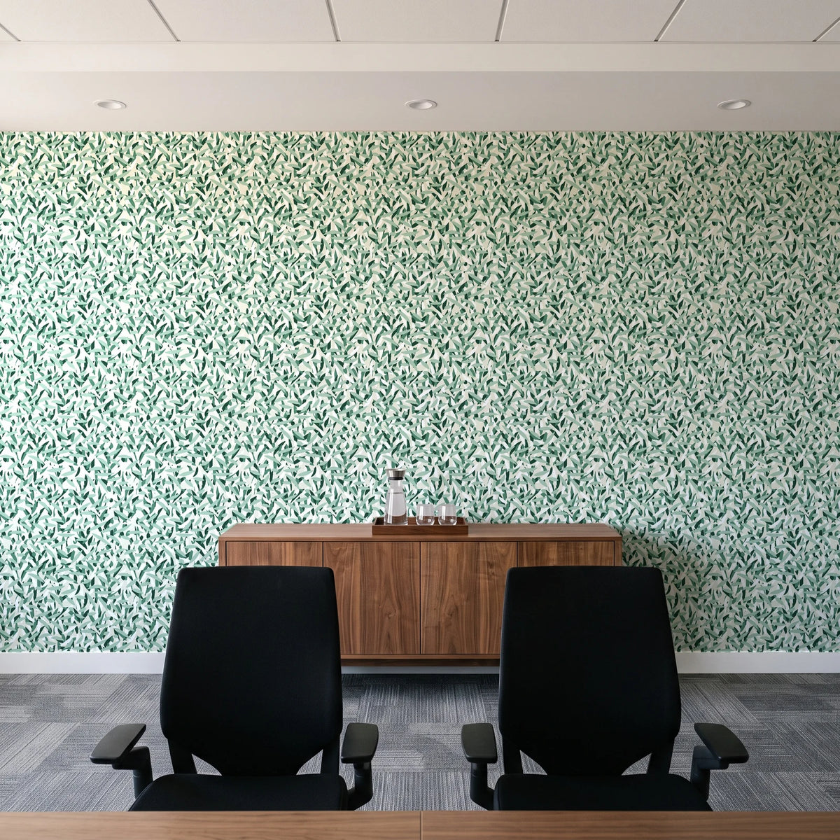 Drifting Petals Emerald abstract petal wallpaper above a walnut credenza in a modern conference room