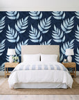 Driftwood Fern Midnight fern frond wallpaper behind a queen bed in a bright coastal bedroom