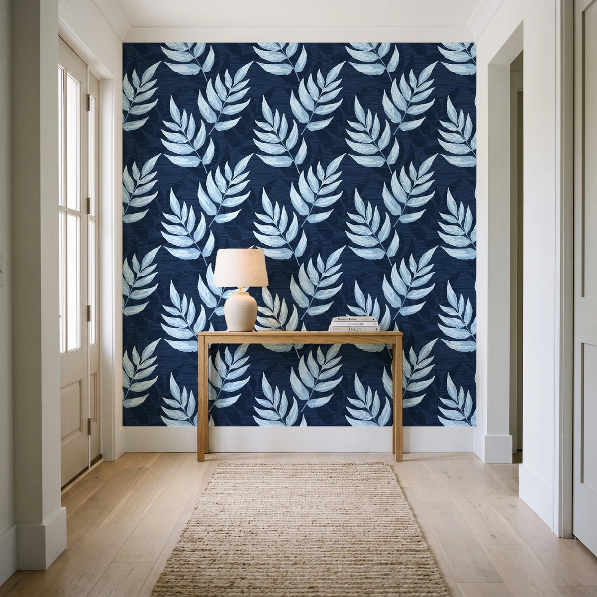 Driftwood Fern Midnight fern frond wallpaper behind a console table in a light entry hallway