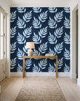Driftwood Fern Midnight fern frond wallpaper behind a console table in a light entry hallway