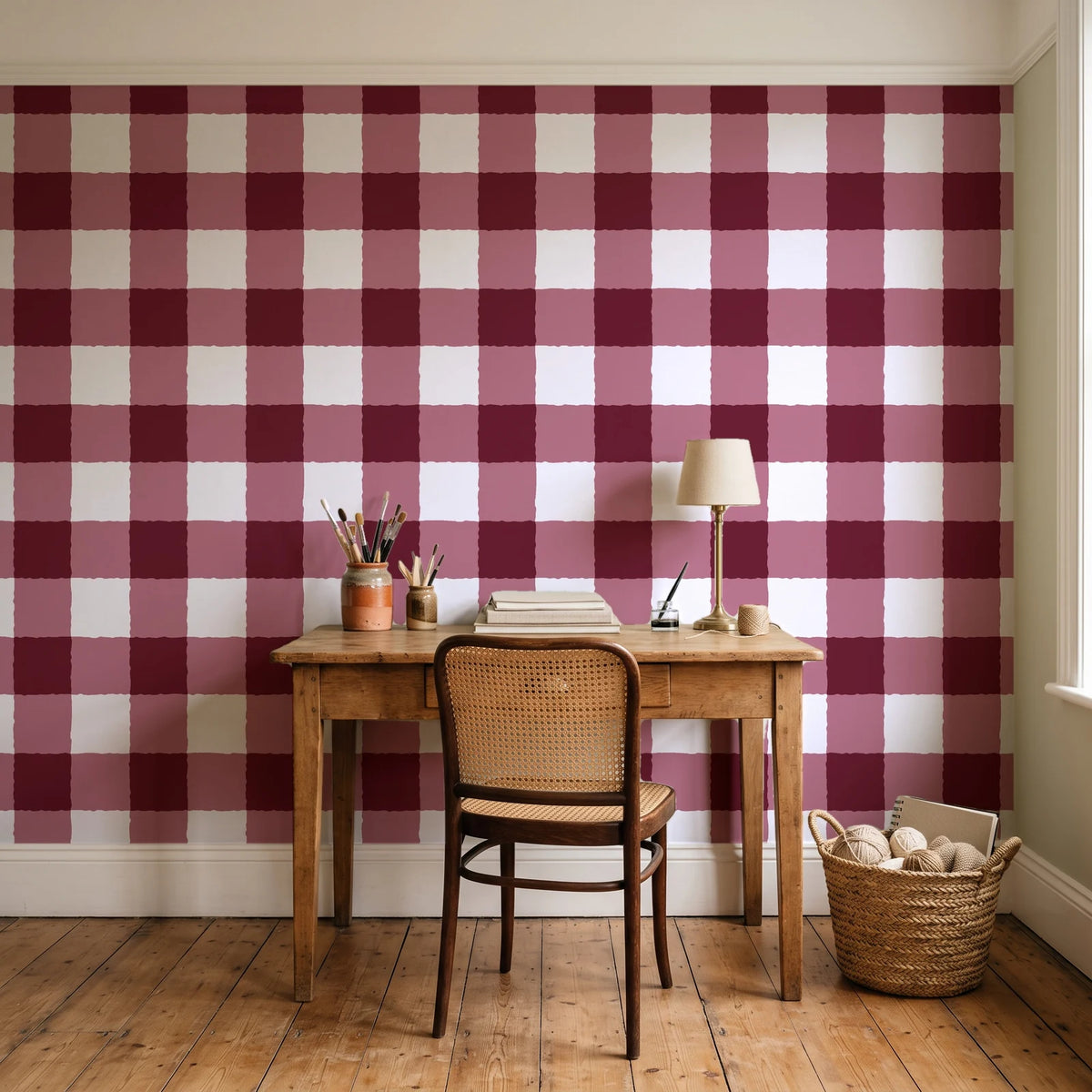 Dune Plaid Oxblood gingham check wallpaper behind a vintage writing desk in a cozy craft-room home office