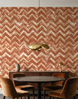 Dusk Passage Terracotta chevron wallpaper behind a walnut credenza and round table in an elegant dining room