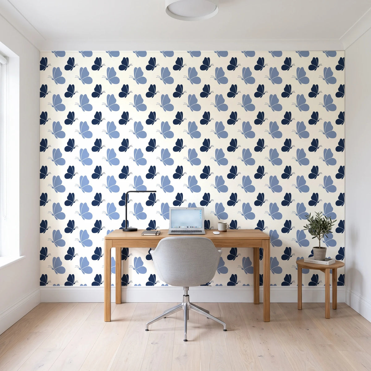 Dust & Wing Navy butterflies wallpaper behind a modern oak desk in a bright home office