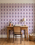 Ember & Iron Plum retro ogee wallpaper behind a vintage writing desk in a cozy craft-room home office