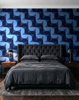 Ember Mosaic Midnight retro geometric wallpaper behind a tufted headboard in a dark, moody bedroom