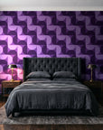 Ember Mosaic Plum retro geometric wallpaper behind a tufted headboard in a dark, moody bedroom