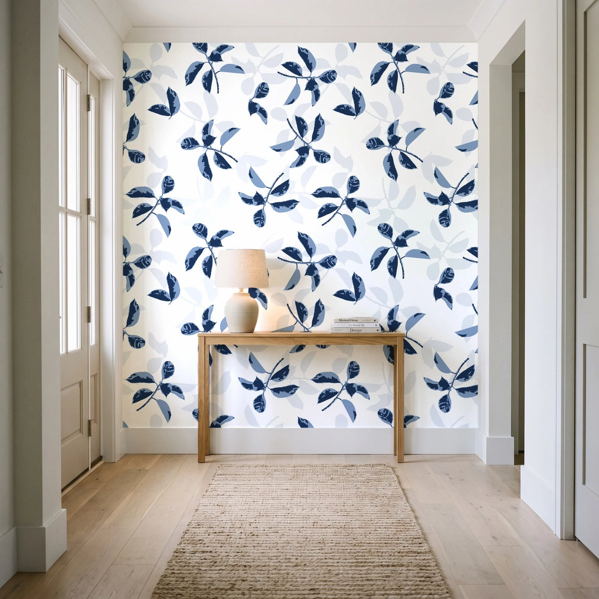 Falling Softly Navy botanical leaf wallpaper behind a console table in a light entry hallway