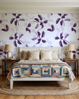 Falling Softly Plum botanical leaf wallpaper behind a white cottage bed with a patchwork quilt in a cozy cottagecore bedroom
