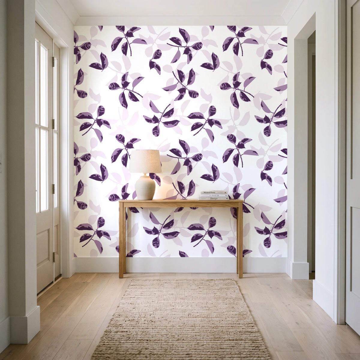 Falling Softly Plum botanical leaf wallpaper behind a console table in a light entry hallway