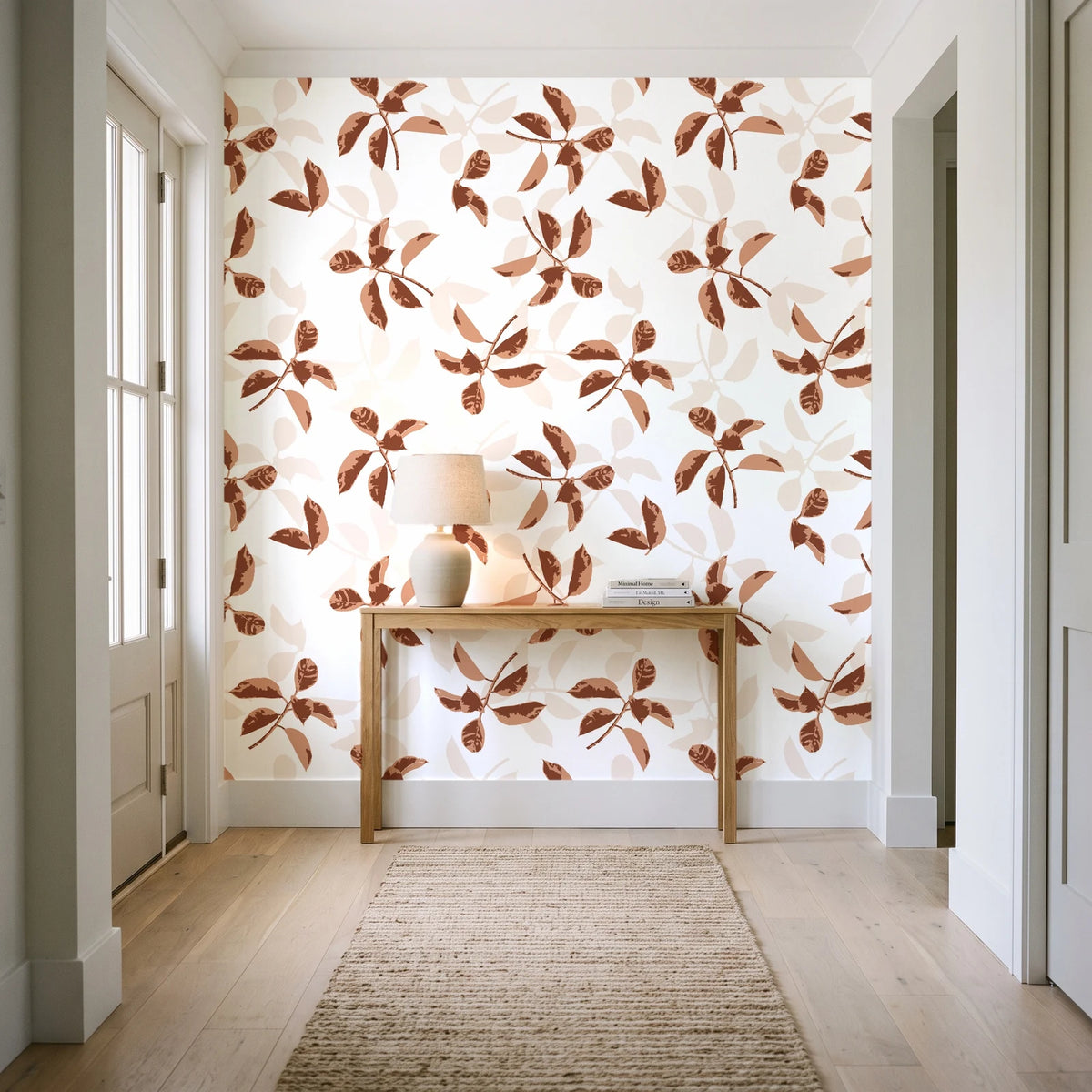 Falling Softly Terracotta botanical leaf wallpaper behind a console table in a light entry hallway