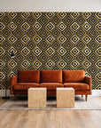 Fern Lattice Gilt hand-drawn diamond wallpaper behind a rust velvet sofa in a bright coworking lounge