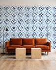 Fern Lattice Navy hand-drawn diamond wallpaper behind a rust velvet sofa in a bright coworking lounge