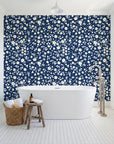 First Bloom Navy ditsy floral wallpaper behind a freestanding tub in a bright coastal bathroom