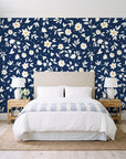 First Bloom Navy ditsy floral wallpaper behind a queen bed in a bright coastal bedroom
