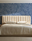 Forest Leaf Slate Blue botanical leaf wallpaper behind a channel-tufted bed in a calm primary bedroom