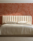 Forest Leaf Terracotta botanical leaf wallpaper behind a channel-tufted bed in a calm primary bedroom
