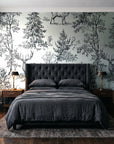 Frost & Fable Graphite woodland toile wallpaper behind a tufted headboard in a dark, moody bedroom