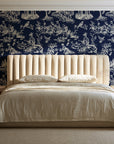 Garden Folly Midnight pastoral toile wallpaper behind a channel-tufted bed in a calm primary bedroom