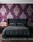 Gentlebotan Plum botanical damask wallpaper behind a tufted headboard in a dark, moody bedroom