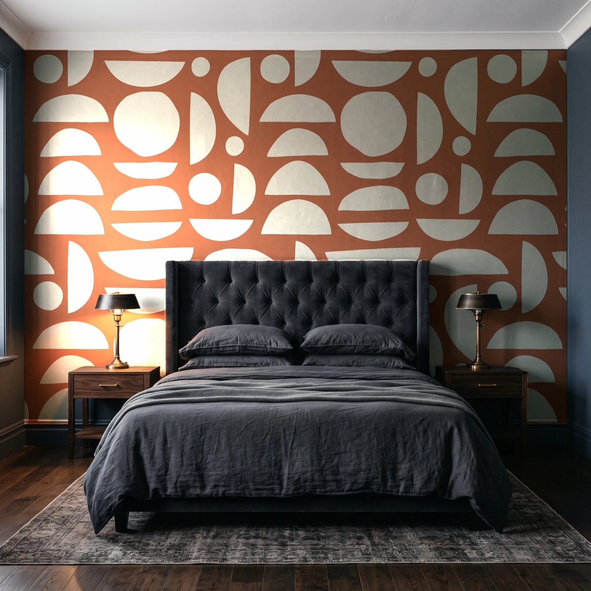 Geo Eclipse Terracotta organic shapes wallpaper behind a tufted headboard in a dark, moody bedroom