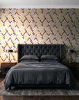 Gilded Crossing Oxblood chevron geometric wallpaper behind a tufted headboard in a dark, moody bedroom