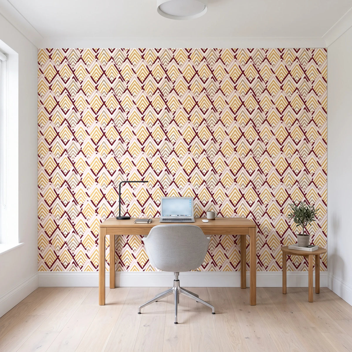 Gilded Crossing Oxblood chevron geometric wallpaper behind a modern oak desk in a bright home office