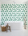 Gilded Frond Emerald leaf wallpaper behind a freestanding tub in a bright coastal bathroom