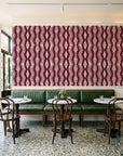 Gilded Rain Oxblood geometric wallpaper above a green leather banquette in a sunlit neighborhood cafe