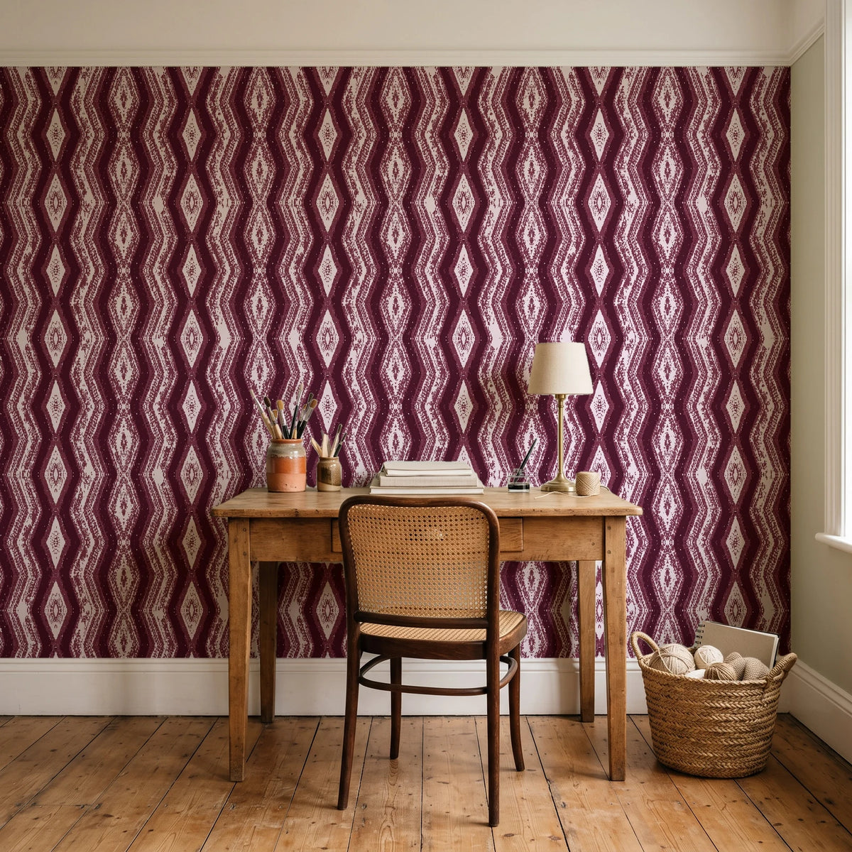 Gilded Rain Oxblood geometric wallpaper behind a vintage writing desk in a cozy craft-room home office